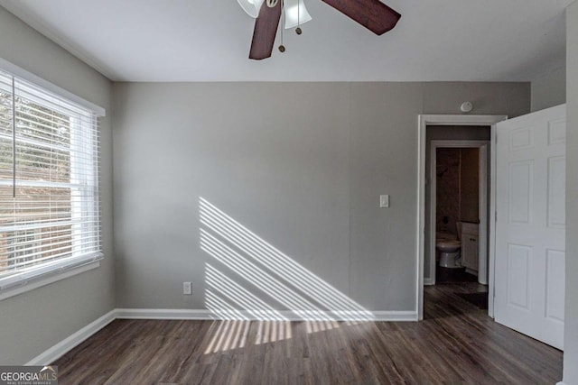 empty room featuring ceiling fan, a healthy amount of sunlight, and dark hardwood / wood-style flooring