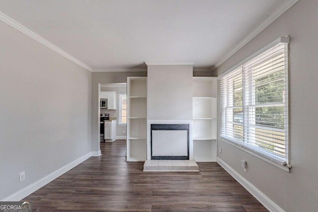 unfurnished living room featuring dark wood-type flooring, a fireplace, ornamental molding, and a healthy amount of sunlight