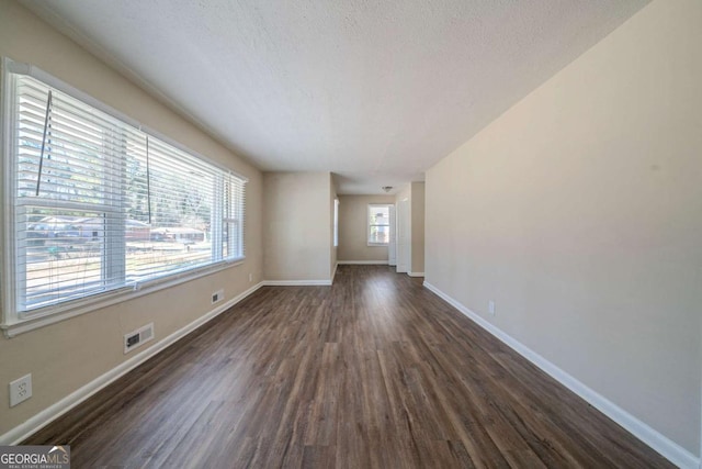 empty room with dark wood-type flooring and a textured ceiling