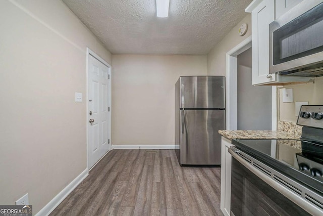 kitchen featuring appliances with stainless steel finishes, a textured ceiling, white cabinets, and light wood-type flooring