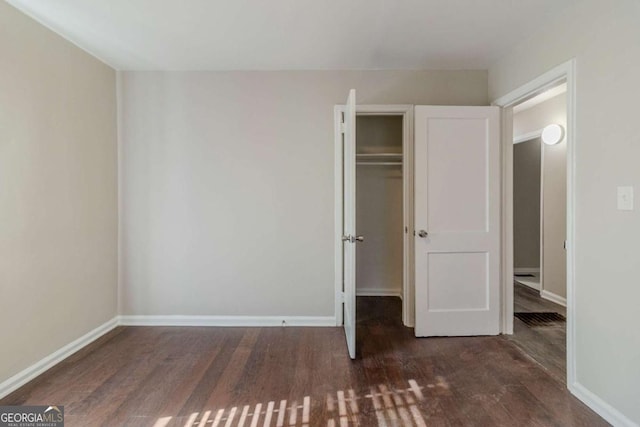 unfurnished bedroom featuring dark hardwood / wood-style floors and a closet