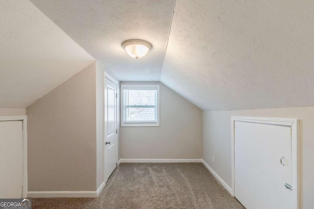 additional living space featuring lofted ceiling, light colored carpet, and a textured ceiling