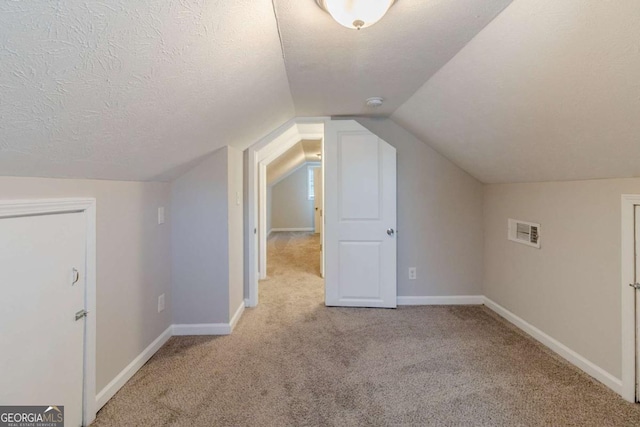 bonus room with vaulted ceiling, light carpet, and a textured ceiling