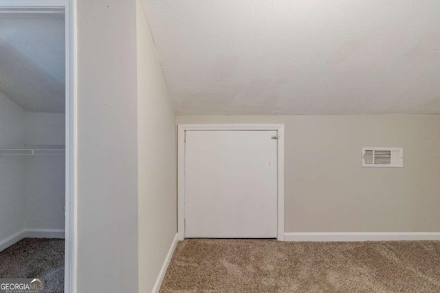 bonus room with carpet floors, vaulted ceiling, and a textured ceiling