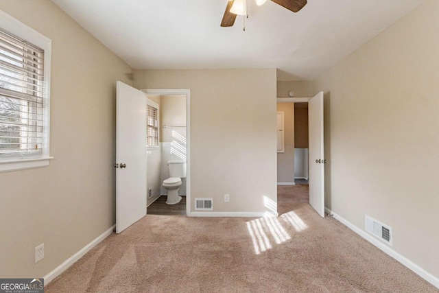 unfurnished bedroom featuring ceiling fan, ensuite bathroom, and carpet flooring