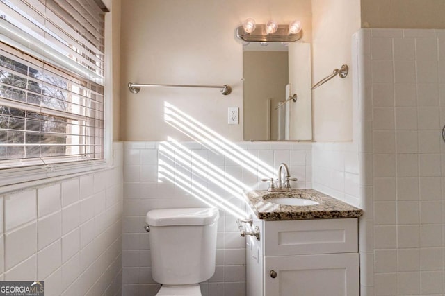 bathroom featuring tile walls, vanity, and toilet