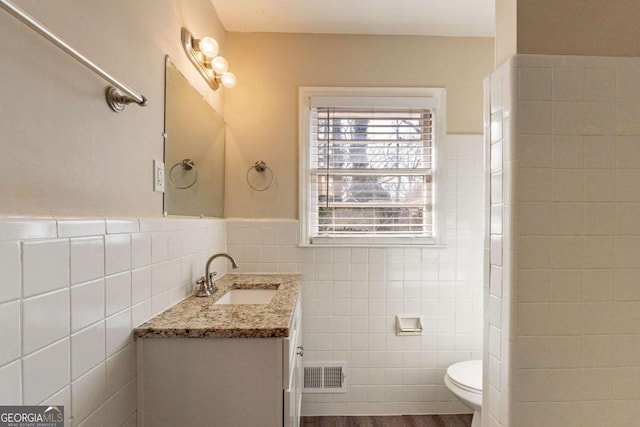 bathroom with hardwood / wood-style floors, vanity, tile walls, and toilet