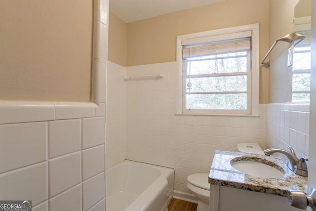 bathroom featuring vanity, toilet, a bathing tub, and a wealth of natural light