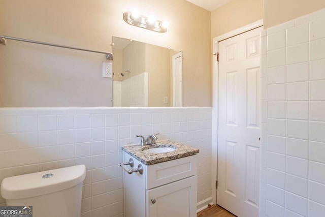 bathroom featuring vanity, a shower, tile walls, and toilet