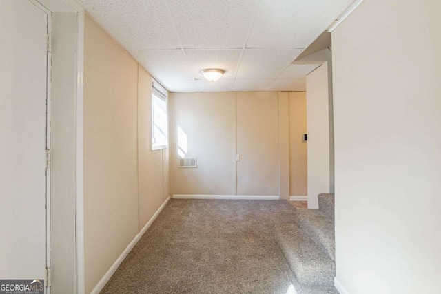 empty room featuring carpet floors and a paneled ceiling