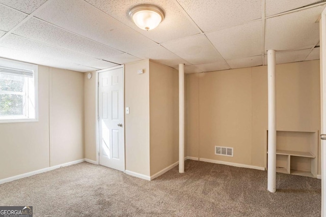 basement featuring a paneled ceiling and carpet