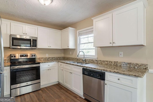 kitchen with sink, white cabinetry, a textured ceiling, stainless steel appliances, and light stone countertops