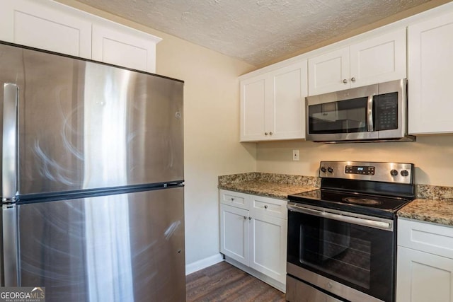 kitchen featuring dark hardwood / wood-style flooring, stone counters, white cabinets, and appliances with stainless steel finishes