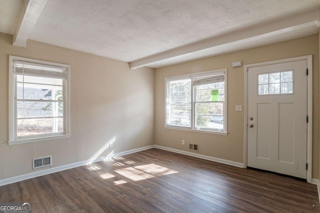 foyer entrance featuring beamed ceiling, dark wood-type flooring, and a textured ceiling