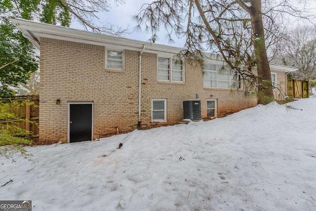 snow covered rear of property featuring cooling unit