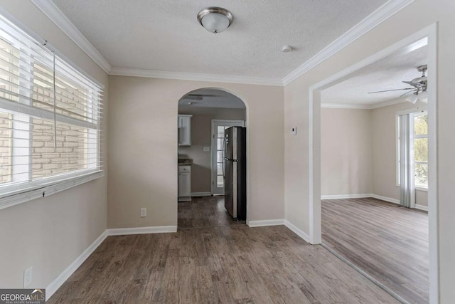 spare room with ceiling fan, ornamental molding, wood-type flooring, and a textured ceiling