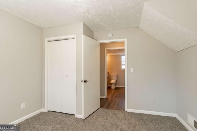 unfurnished bedroom featuring lofted ceiling, carpet floors, and a textured ceiling