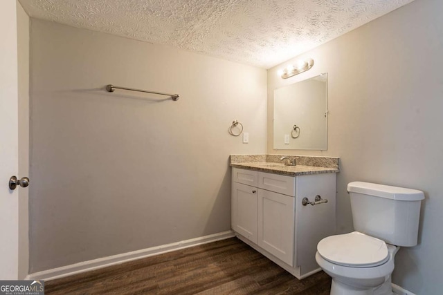 bathroom with vanity, wood-type flooring, toilet, and a textured ceiling