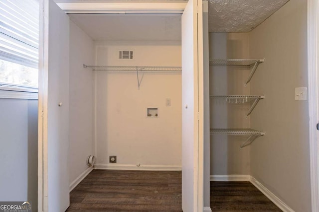 washroom with dark wood-type flooring, washer hookup, and a textured ceiling