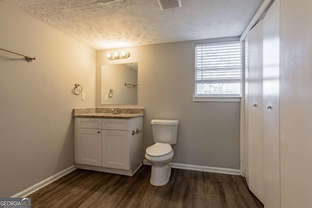 bathroom featuring hardwood / wood-style flooring, vanity, toilet, and a textured ceiling