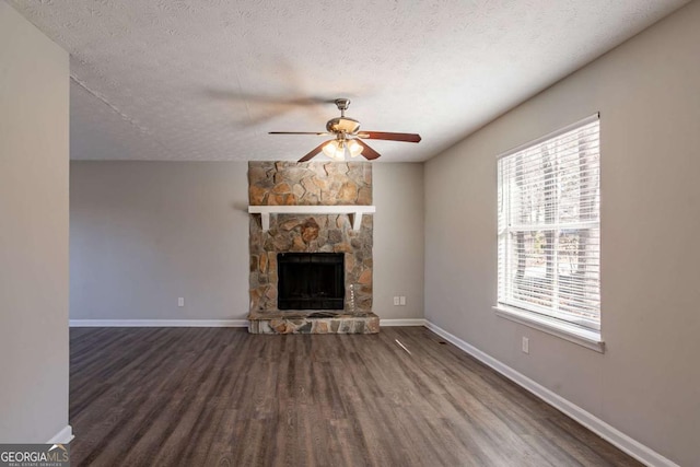 unfurnished living room featuring a fireplace, plenty of natural light, dark hardwood / wood-style floors, and a textured ceiling