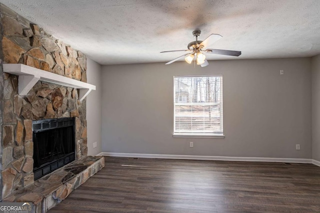 unfurnished living room featuring ceiling fan, a fireplace, dark hardwood / wood-style flooring, and a textured ceiling