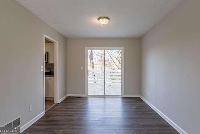 empty room with a textured ceiling and dark hardwood / wood-style flooring