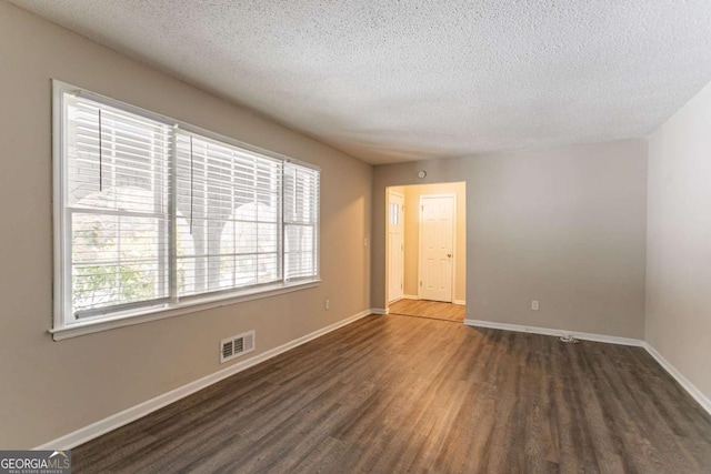 unfurnished room featuring dark hardwood / wood-style flooring and a textured ceiling