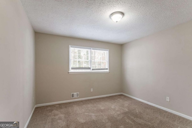 carpeted empty room featuring a textured ceiling