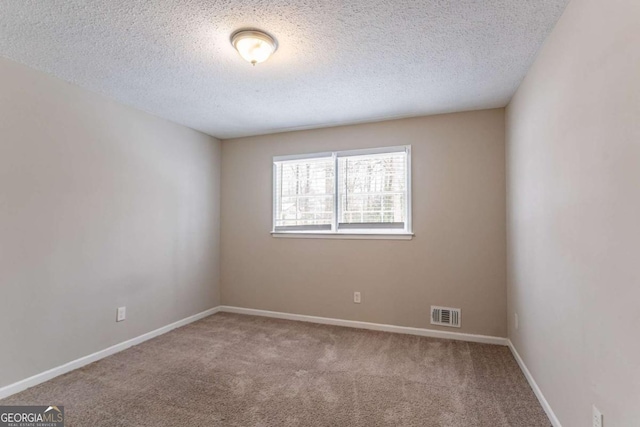 carpeted empty room featuring a textured ceiling