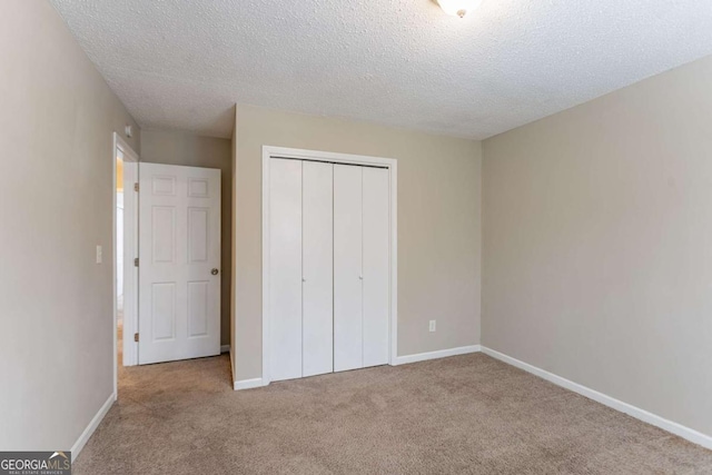 unfurnished bedroom featuring light carpet, a textured ceiling, and a closet