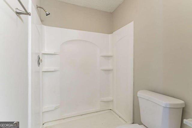 bathroom with toilet, a textured ceiling, and walk in shower