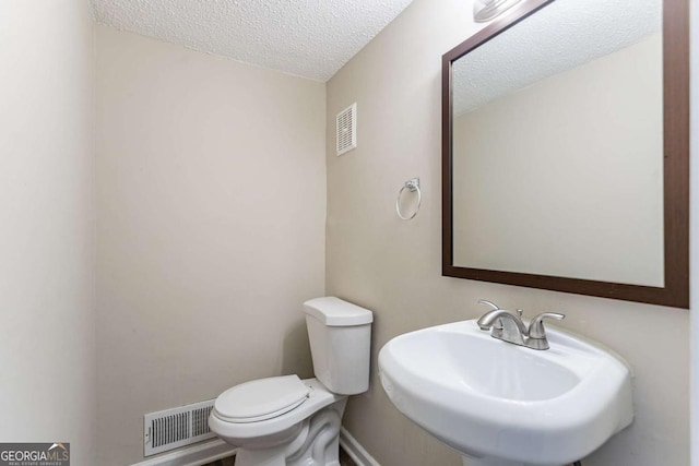 bathroom featuring sink, a textured ceiling, and toilet