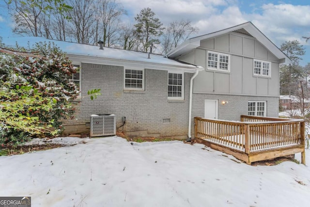 snow covered back of property with central AC and a deck