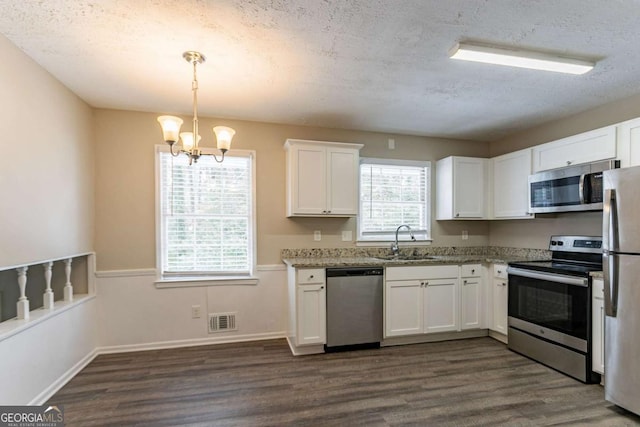 kitchen with sink, a textured ceiling, pendant lighting, stainless steel appliances, and white cabinets