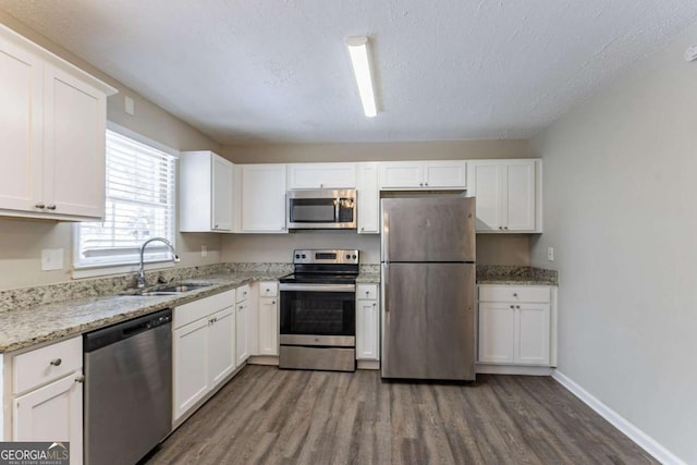 kitchen with sink, light stone counters, a textured ceiling, stainless steel appliances, and white cabinets