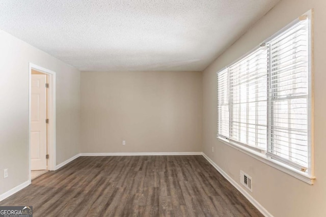 unfurnished room with dark hardwood / wood-style floors and a textured ceiling