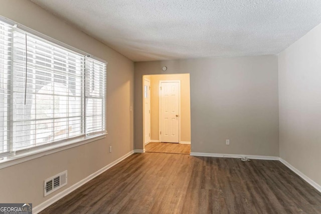 empty room with dark wood-type flooring and a textured ceiling