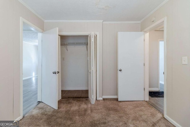 unfurnished bedroom with crown molding, carpet, and a closet