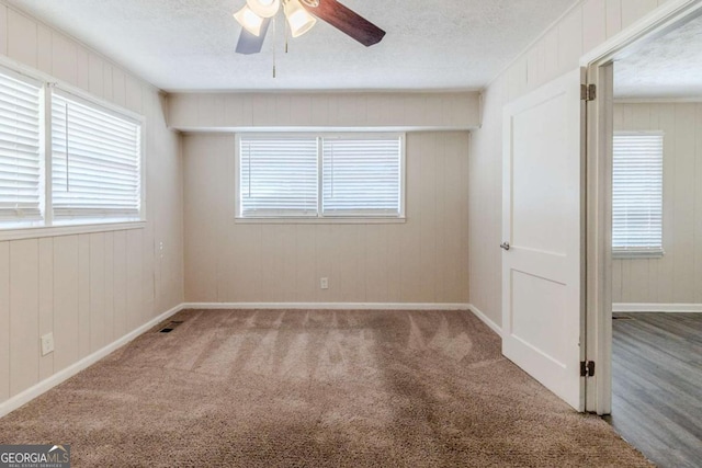 carpeted empty room with ceiling fan and a textured ceiling