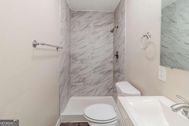 bathroom with tiled shower, vanity, and toilet