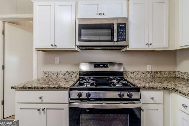 kitchen with light stone counters, range with gas cooktop, and white cabinets