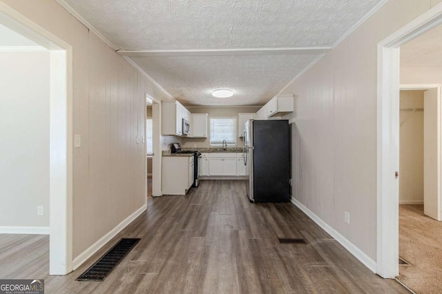 kitchen featuring sink, crown molding, appliances with stainless steel finishes, white cabinetry, and a textured ceiling