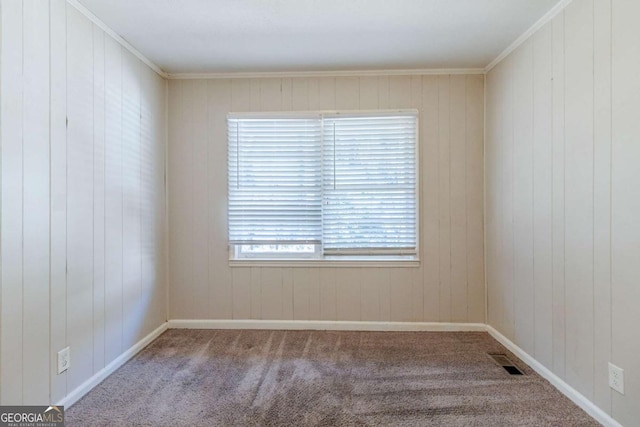 carpeted empty room featuring crown molding and wood walls