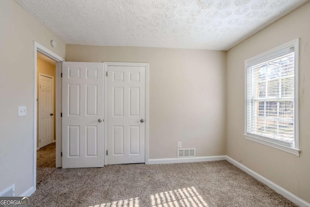 unfurnished bedroom with light colored carpet, a closet, and a textured ceiling