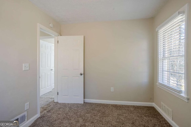 carpeted empty room featuring a textured ceiling