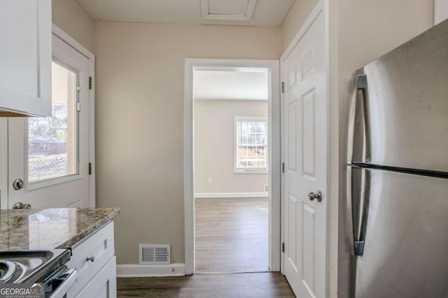 kitchen featuring light stone counters, dark wood-type flooring, stainless steel appliances, and white cabinets