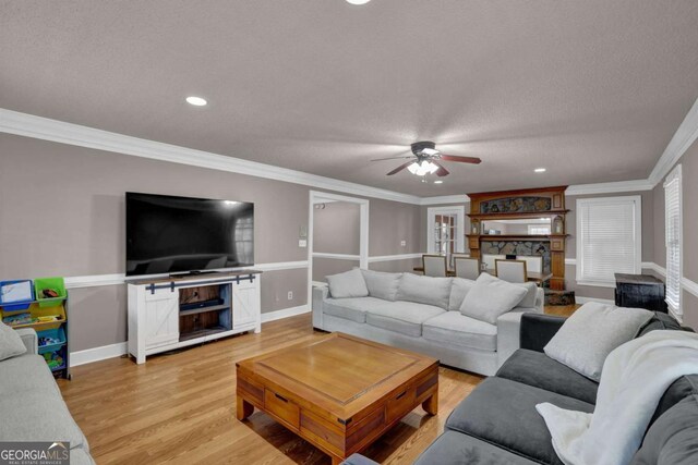 living room featuring crown molding, ceiling fan, a textured ceiling, and light hardwood / wood-style flooring