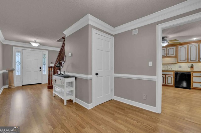 foyer with ornamental molding, a textured ceiling, and light hardwood / wood-style flooring