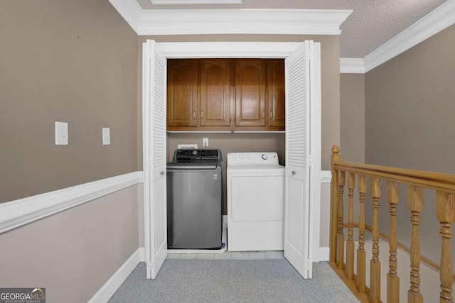 laundry room with ornamental molding, washing machine and dryer, cabinets, and a textured ceiling